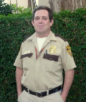 Man in a sheriff's uniform standing outdoors.